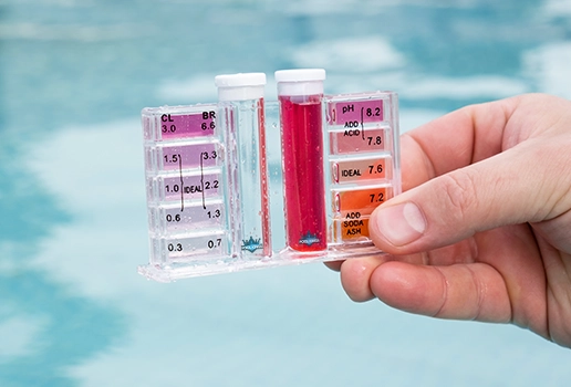 Hand holding a water pH tester during professional pool water testing by Commercial Pool Kings.